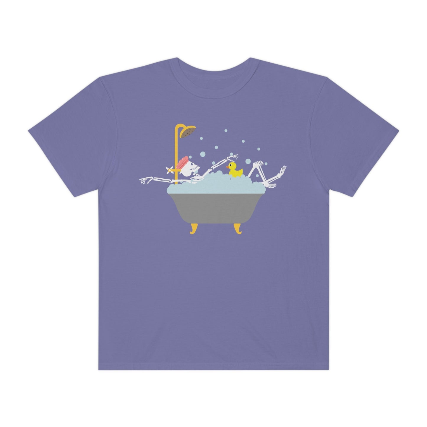 A woman wearing a cute light blue colored shirt with a female skeleton wearing a pink bath cap is taking a bubble bath with a yellow rubber ducky, the bath is gold and gray colored and the air is filled with bubbles.