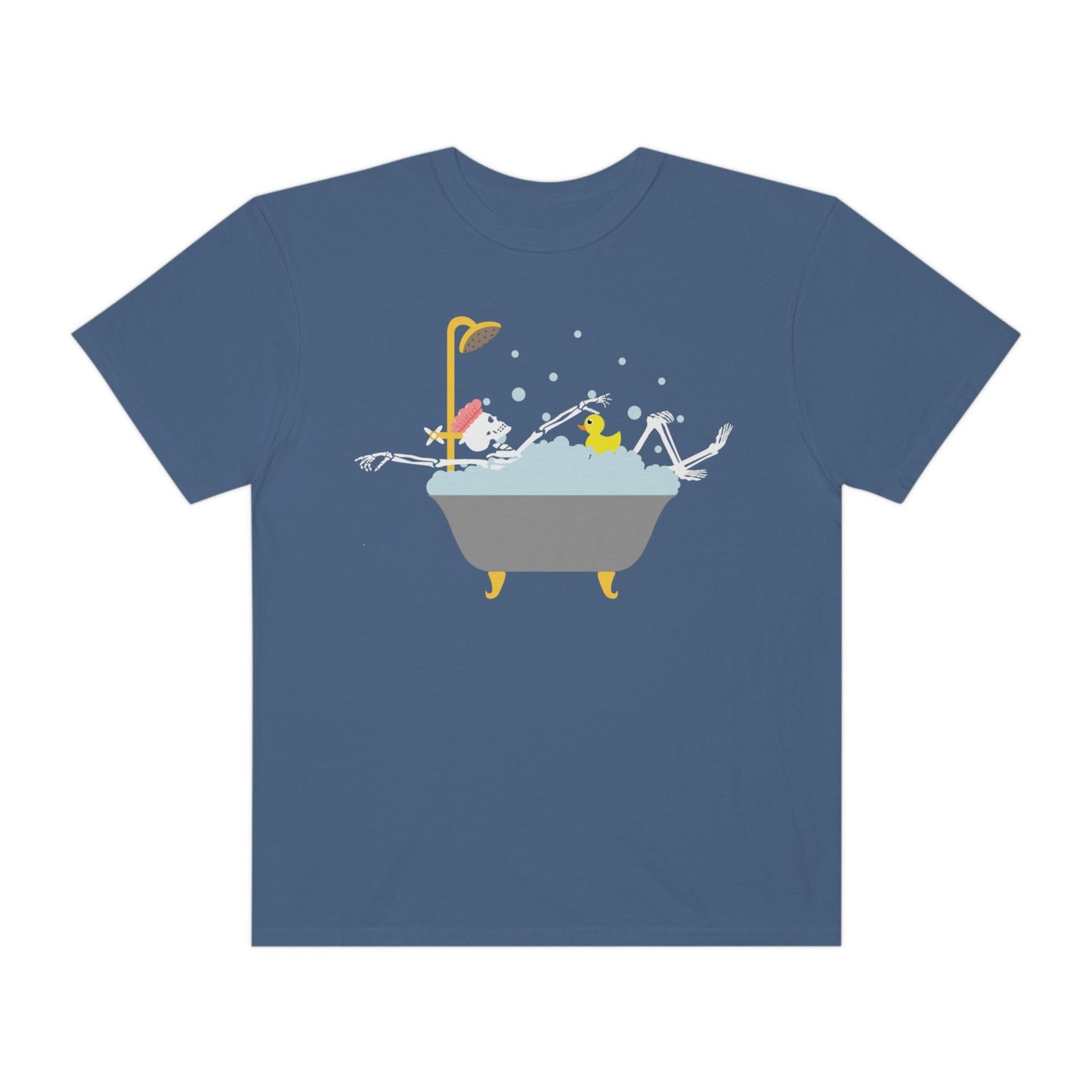 A woman wearing a cute light blue colored shirt with a female skeleton wearing a pink bath cap is taking a bubble bath with a yellow rubber ducky, the bath is gold and gray colored and the air is filled with bubbles.