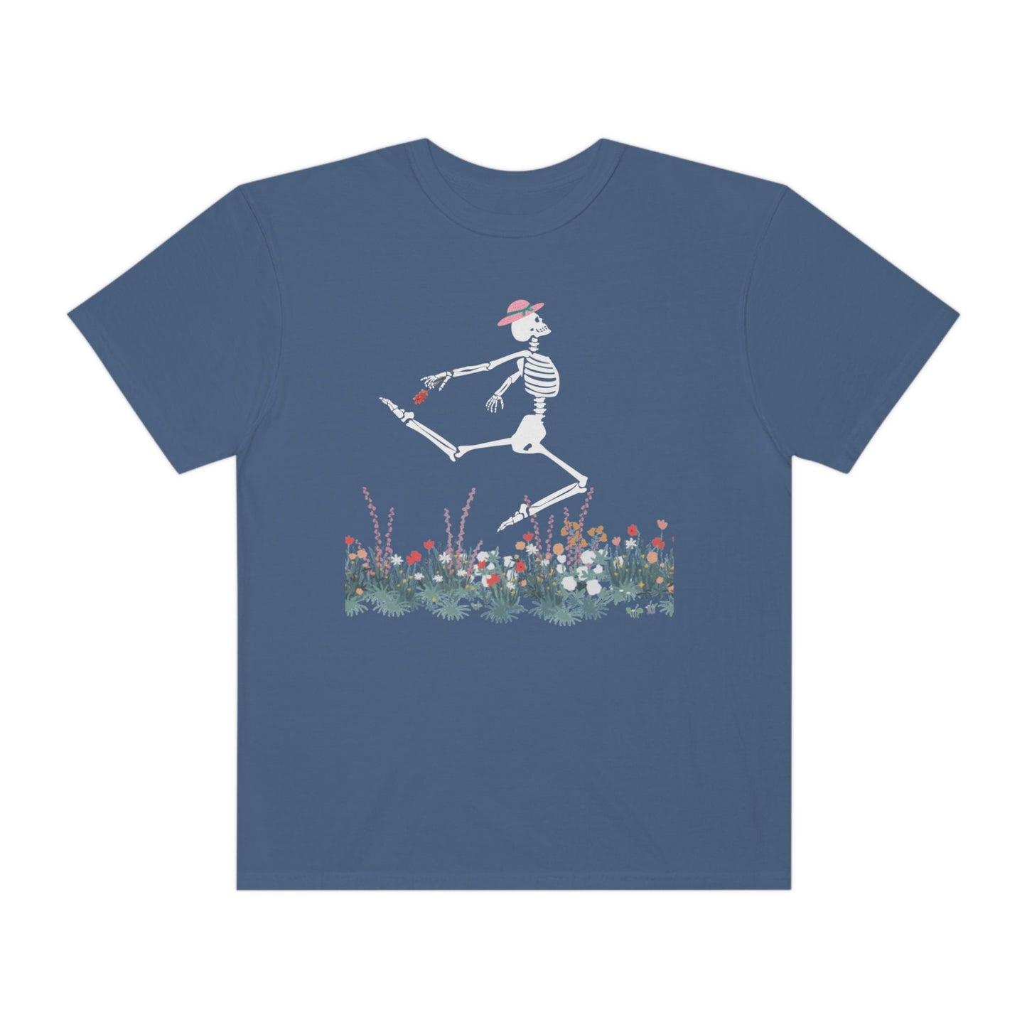 A cute light blue colored shirt with a white female skeleton in a pink bonnet holding a red flower dancing in the air above a meadow of flowers.