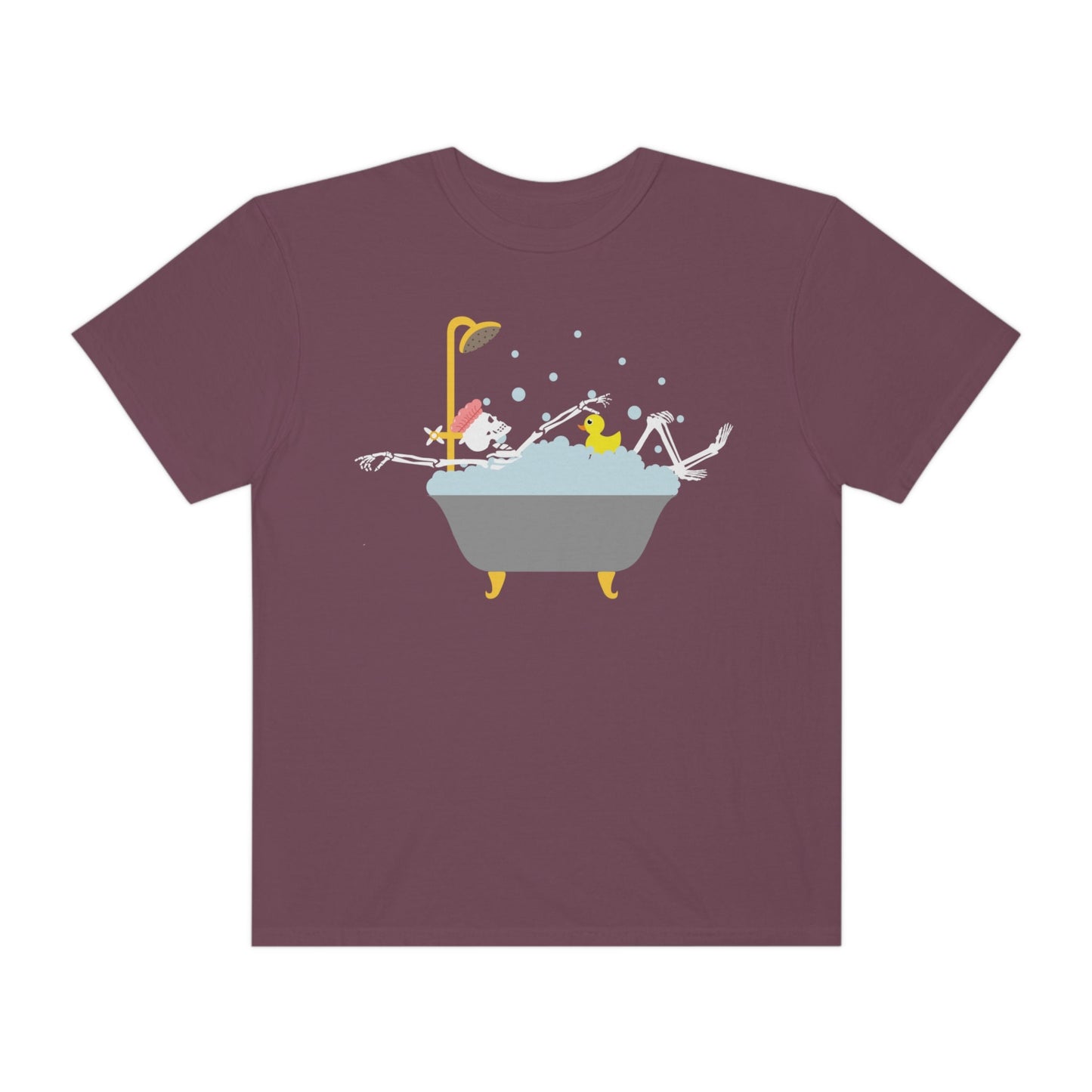 A woman wearing a cute maroon colored shirt with a female skeleton wearing a pink bath cap is taking a bubble bath with a yellow rubber ducky, the bath is gold and gray colored and the air is filled with bubbles.
