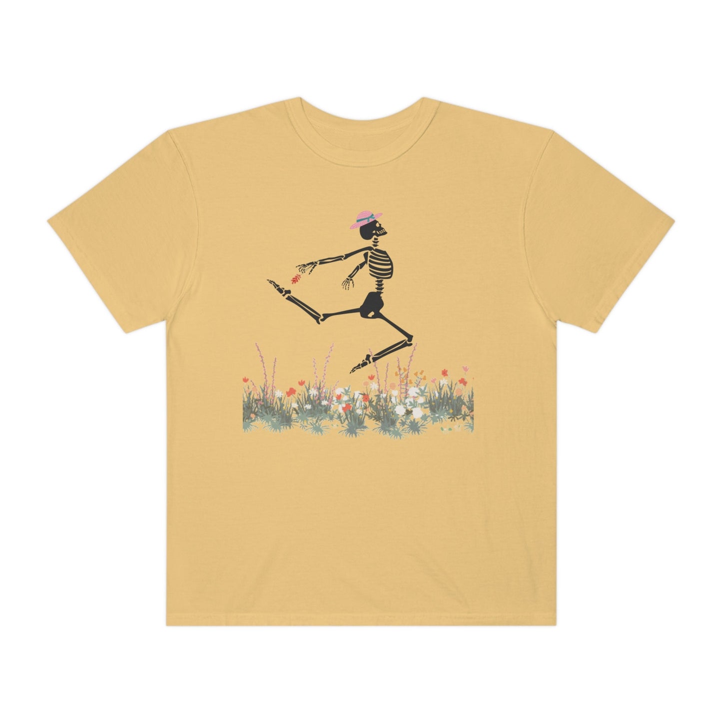 A cute mustard colored shirt with a white female skeleton in a pink bonnet holding a red flower dancing in the air above a meadow of flowers.
