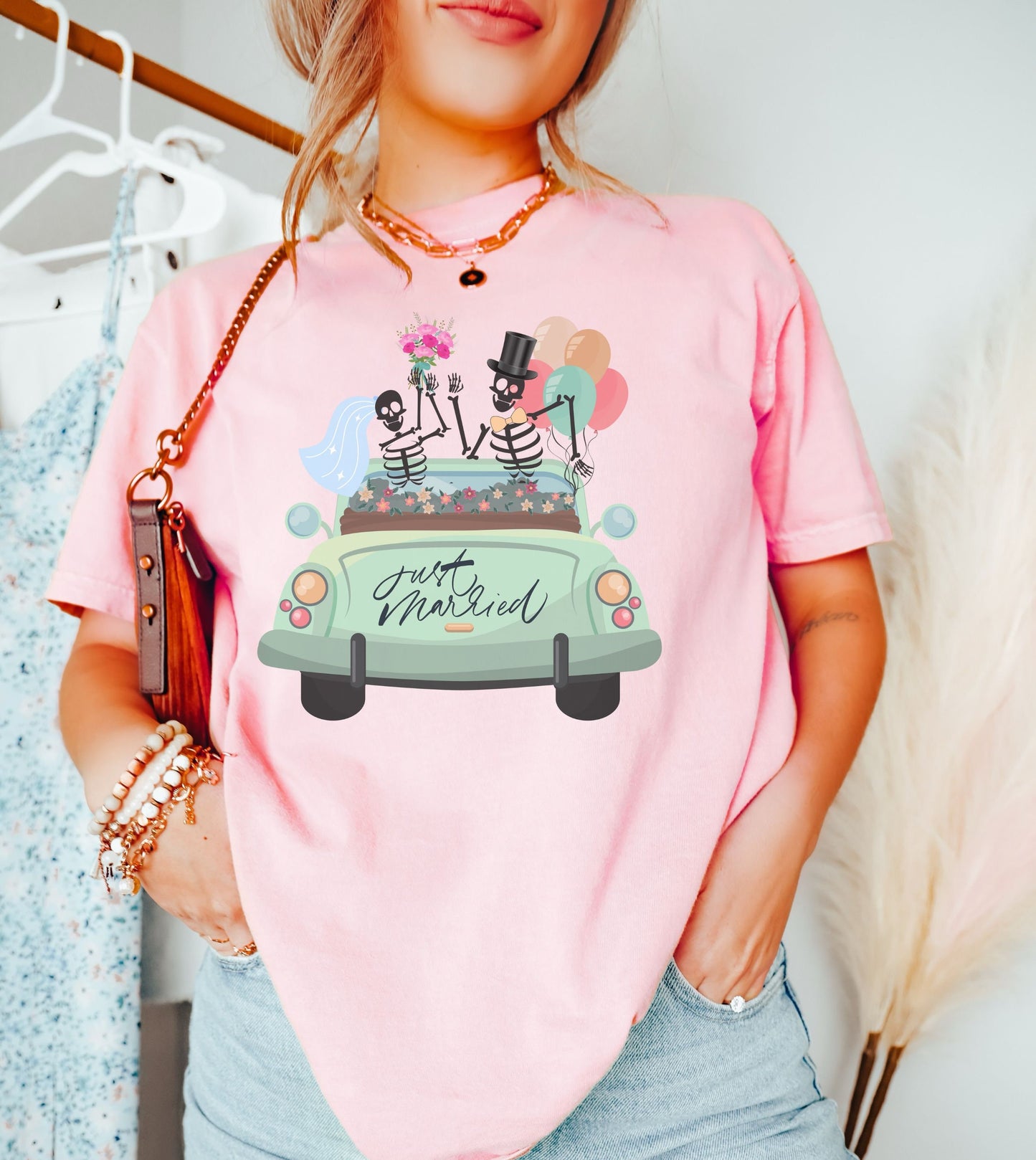 A woman wearing a cute light pink colored shirt with a newlywed couple holding flowers and balloons waving goodbye from a light green car with the text Just Married on the rear of the vehicle.