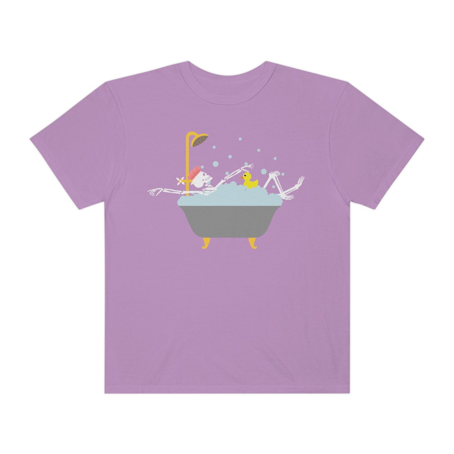 A woman wearing a cute light purple colored shirt with a female skeleton wearing a pink bath cap is taking a bubble bath with a yellow rubber ducky, the bath is gold and gray colored and the air is filled with bubbles.