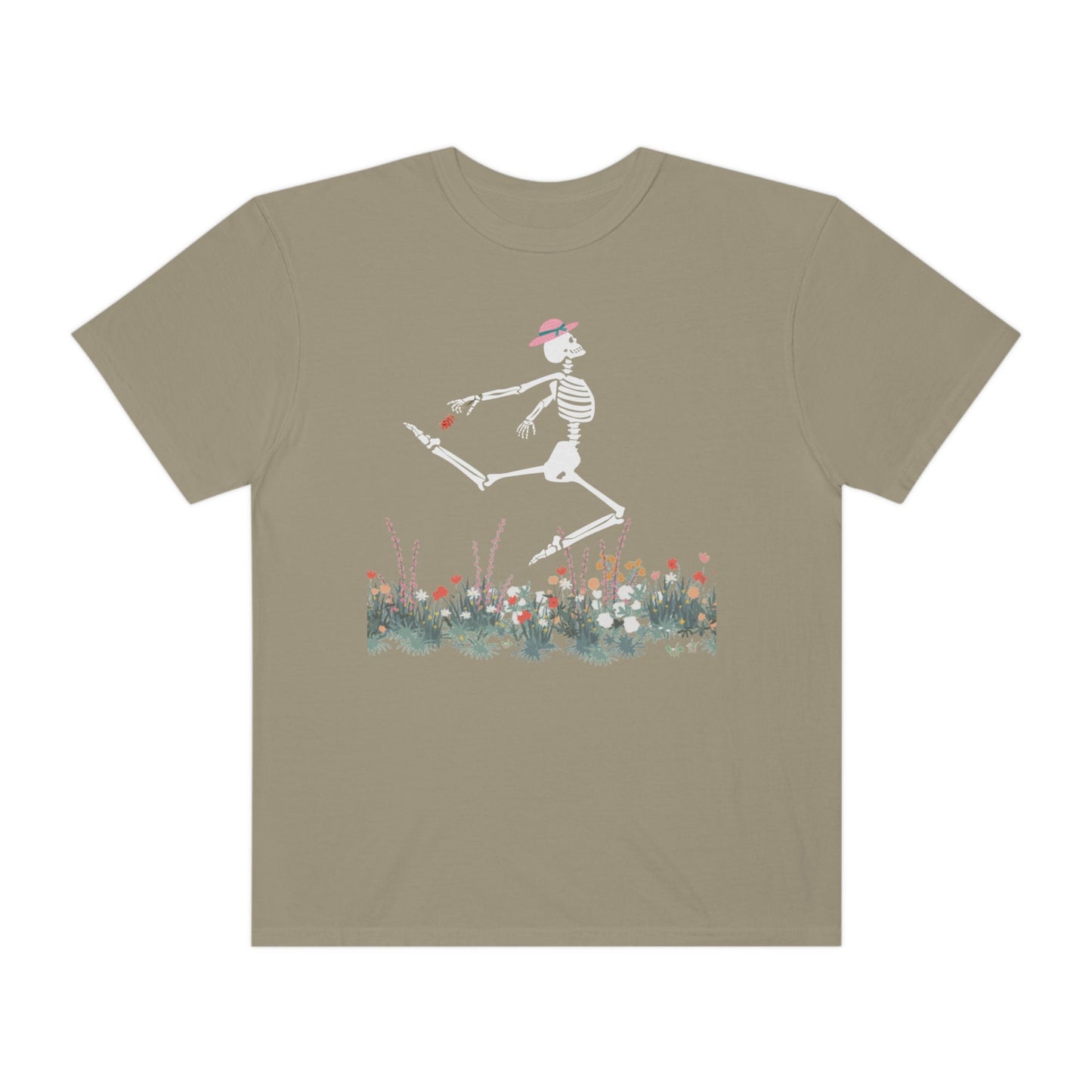 A cute light green colored shirt with a white female skeleton in a pink bonnet holding a red flower dancing in the air above a meadow of flowers.