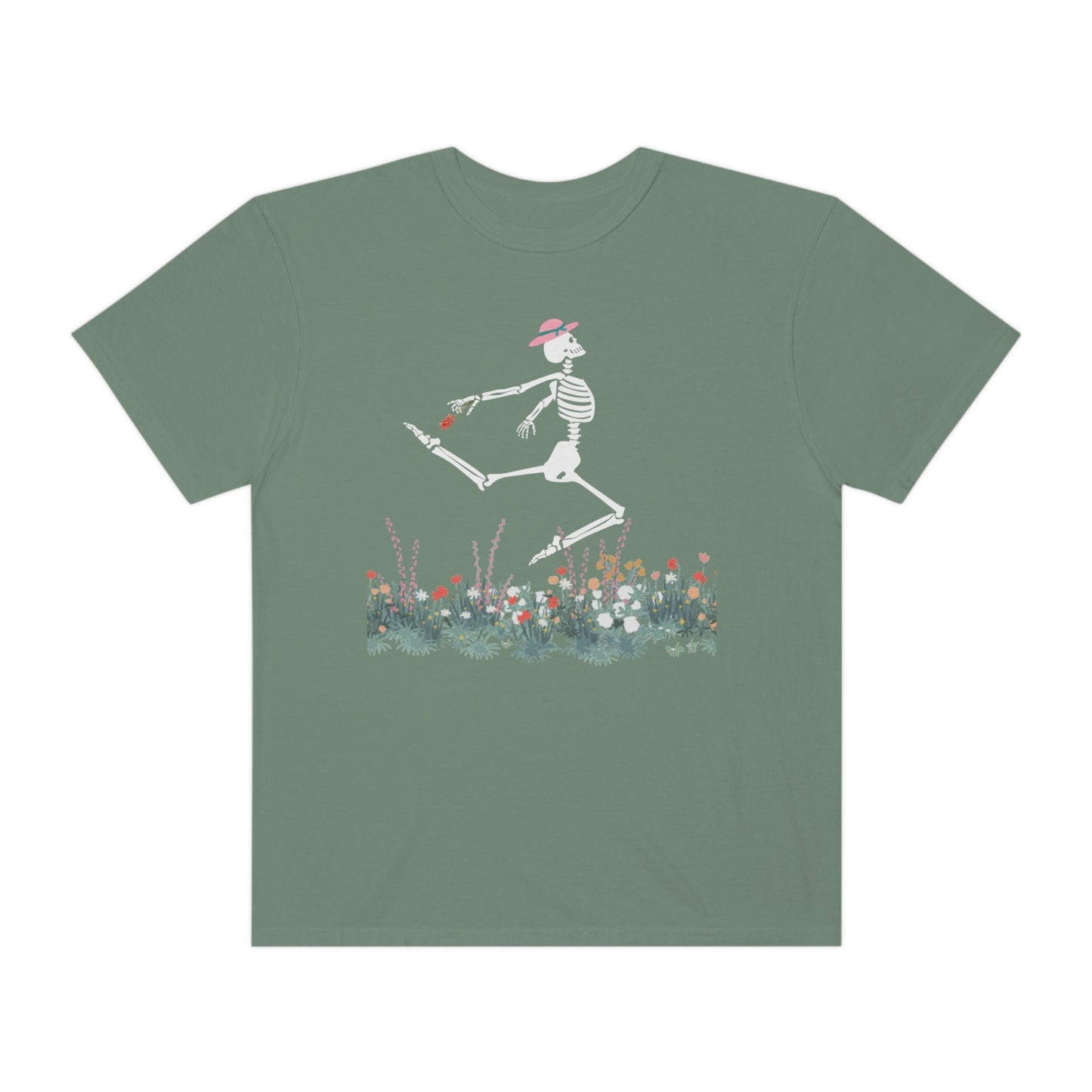 A cute green colored shirt with a white female skeleton in a pink bonnet holding a red flower dancing in the air above a meadow of flowers.