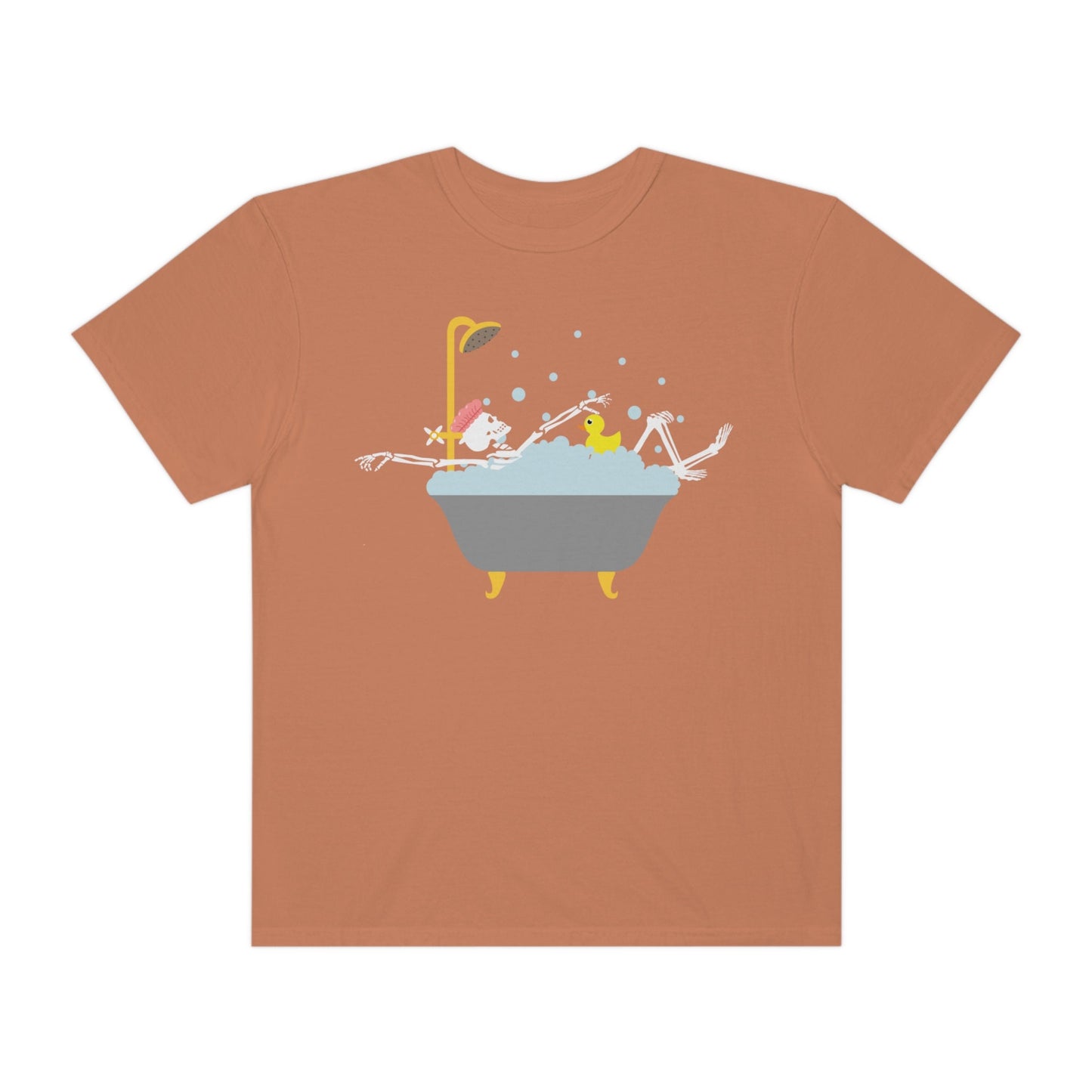 A woman wearing a cute burnt orange colored shirt with a female skeleton wearing a pink bath cap is taking a bubble bath with a yellow rubber ducky, the bath is gold and gray colored and the air is filled with bubbles.