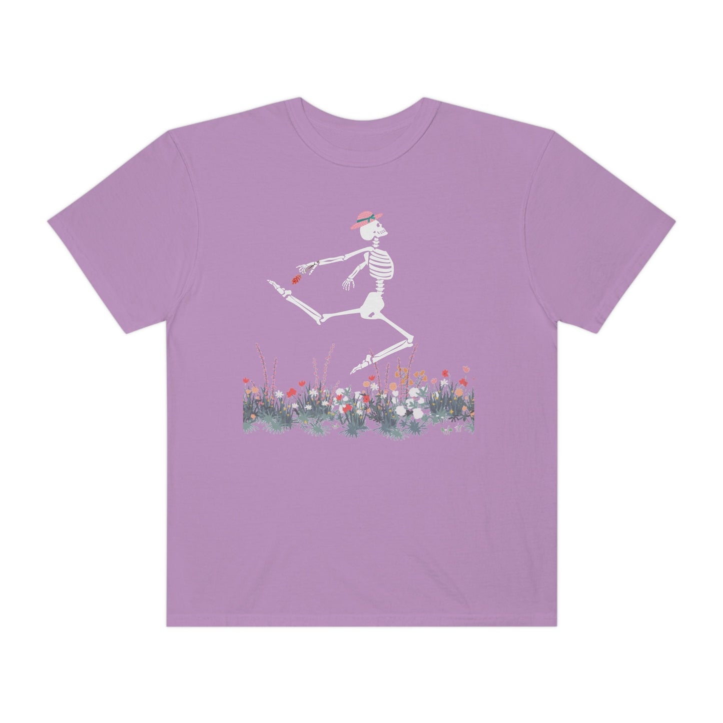 A cute purple colored shirt with a white female skeleton in a pink bonnet holding a red flower dancing in the air above a meadow of flowers.