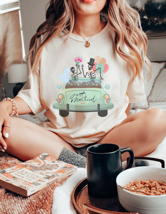 A woman wearing a cute ivory colored shirt with a newlywed couple holding flowers and balloons waving goodbye from a light green car with the text Just Married on the rear of the vehicle.