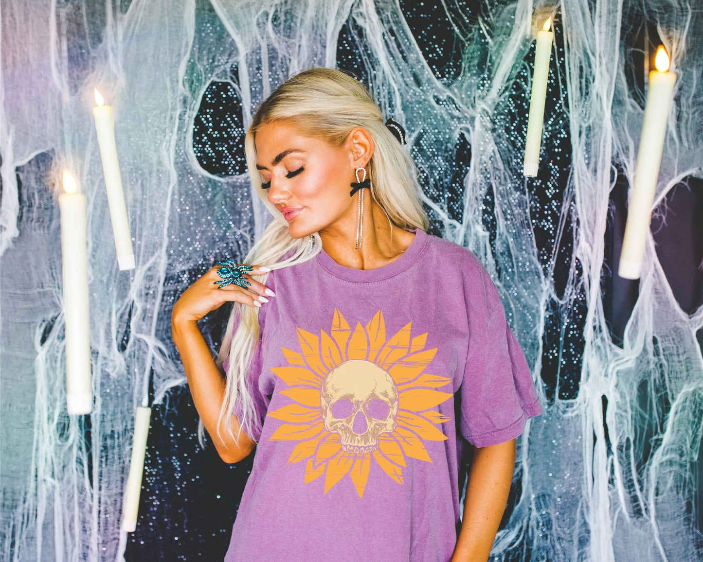 A woman wearing a cute light purple colored shirt with a light yellow skull in the middle of a yellow sunflower.