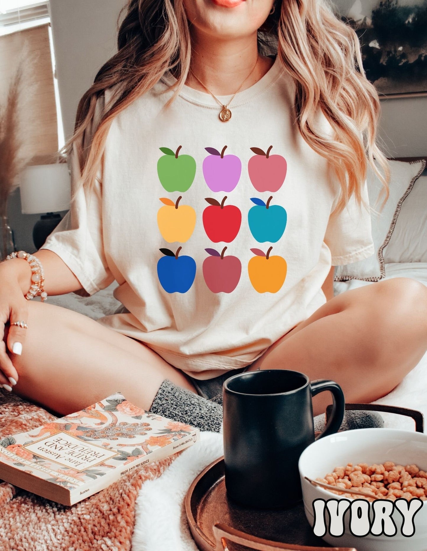 A woman wearing a vintage, ivory colored shirt with three by three rows of nine apples in green, purple, salmon, yellow, red, turquoise, blue, terracotta, and orange colors.