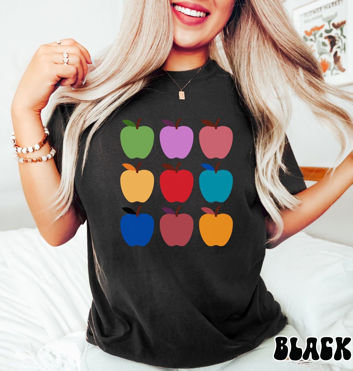 A woman wearing a vintage, black colored shirt with three by three rows of nine apples in green, purple, salmon, yellow, red, turquoise, blue, terracotta, and orange colors.