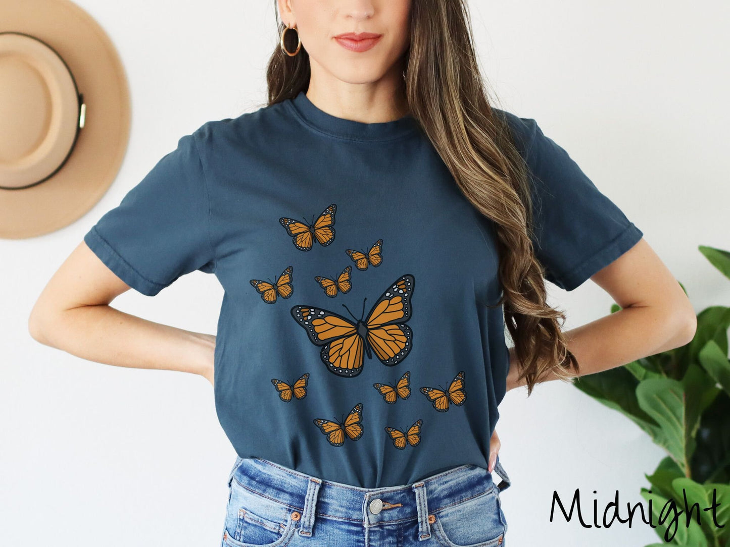 A woman wearing a vintage, midnight colored shirt with a large yellow and black butterfly in the center of the shirt and nine smaller yellow and black monarch butterflies fluttering around behind it.