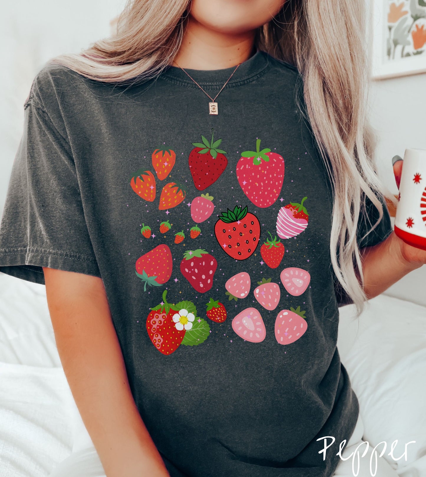 A woman wearing a vintage, pepper colored shirt with many different sizes and colors of strawberries, colors include light red, red, dark red, pink, and blossom.