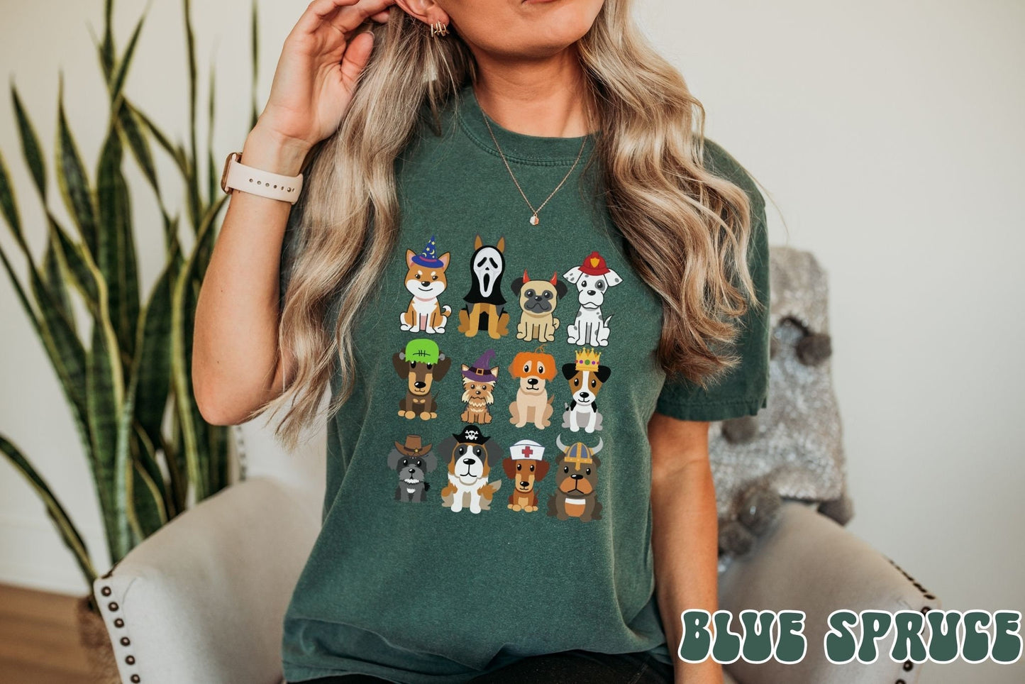 A woman wearing a cute, vintage blue spruce colored Comfort Colors t-shirt with a four by three grid of different breeds of dogs dressed up in Halloween costumes. There is a dog dressed as a fireman and another as a nurse among others.