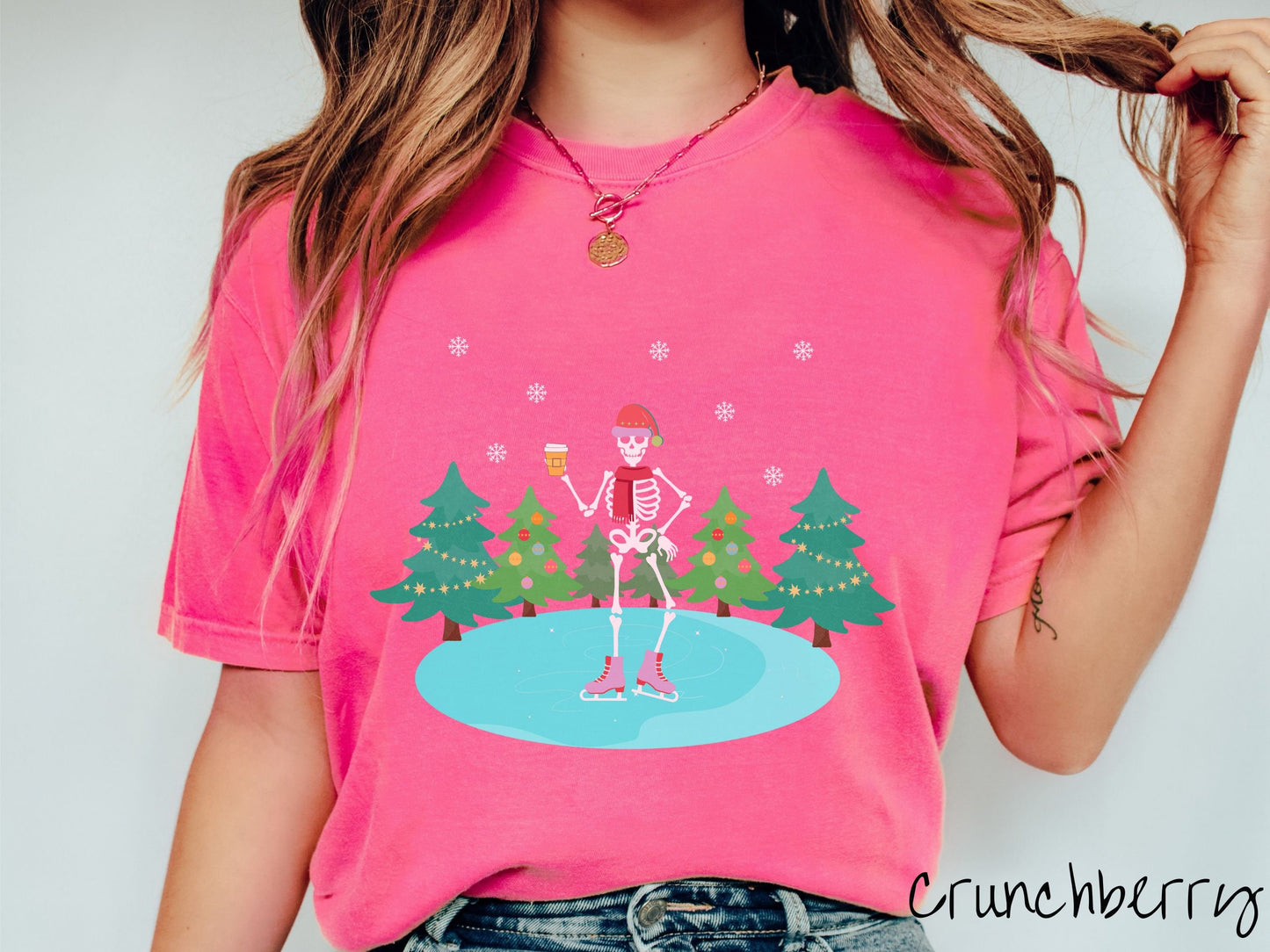 A woman wearing a vintage, crunchberry colored shirt with a female skeleton wearing a red Santa hat, red scarf, red and pink ice skates, and holding a coffee, ice skating on a pond at night with snowflakes and Christmas trees in the background.