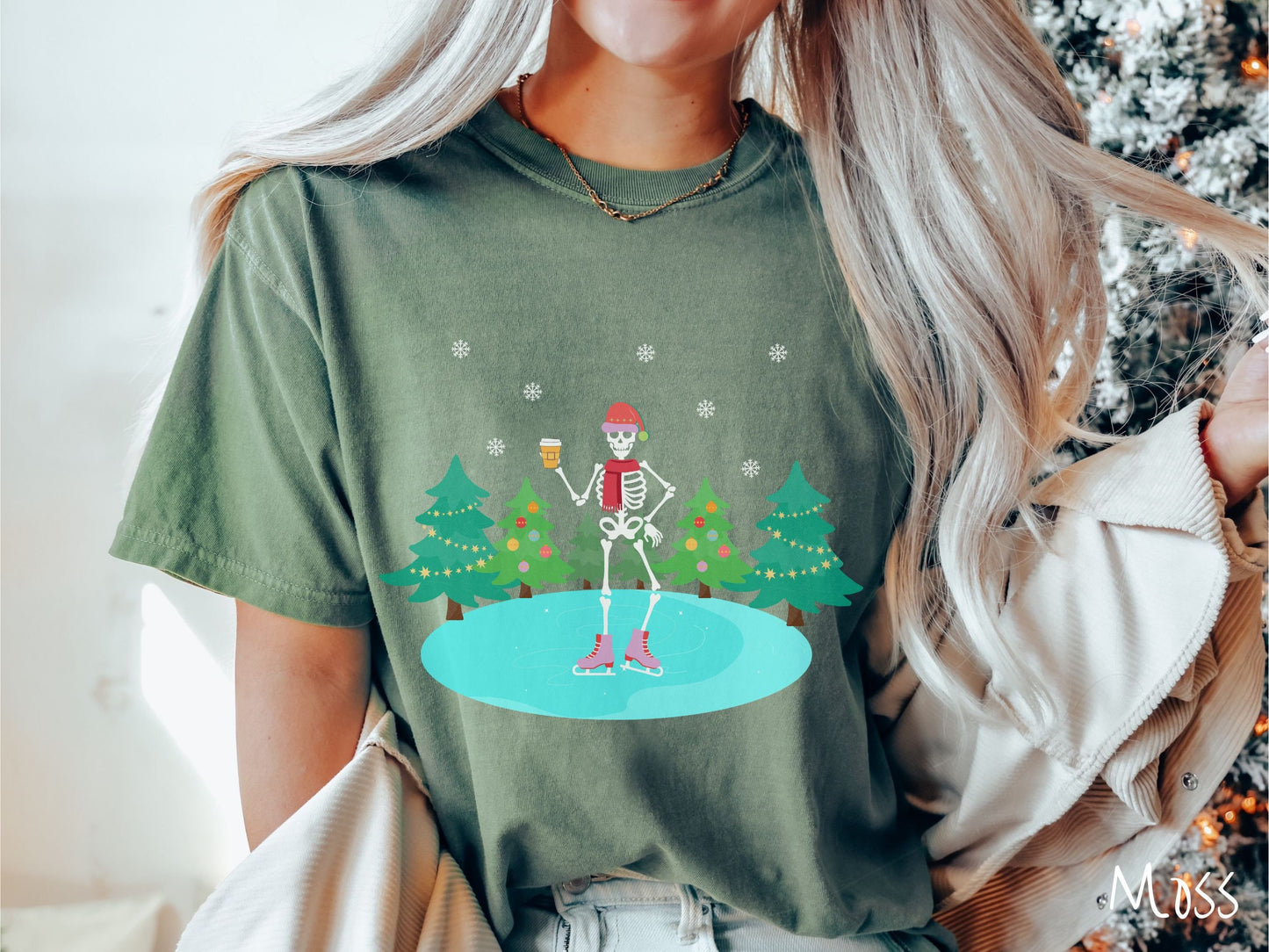 A woman wearing a vintage, moss colored shirt with a female skeleton wearing a red Santa hat, red scarf, red and pink ice skates, and holding a coffee, ice skating on a pond at night with snowflakes in the air and Christmas trees in the background.