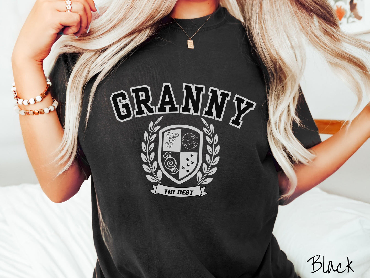 A woman wearing a cute black colored shirt with text saying Granny across the front with a varsity logo underneath with the words The Best centered underneath the logo.