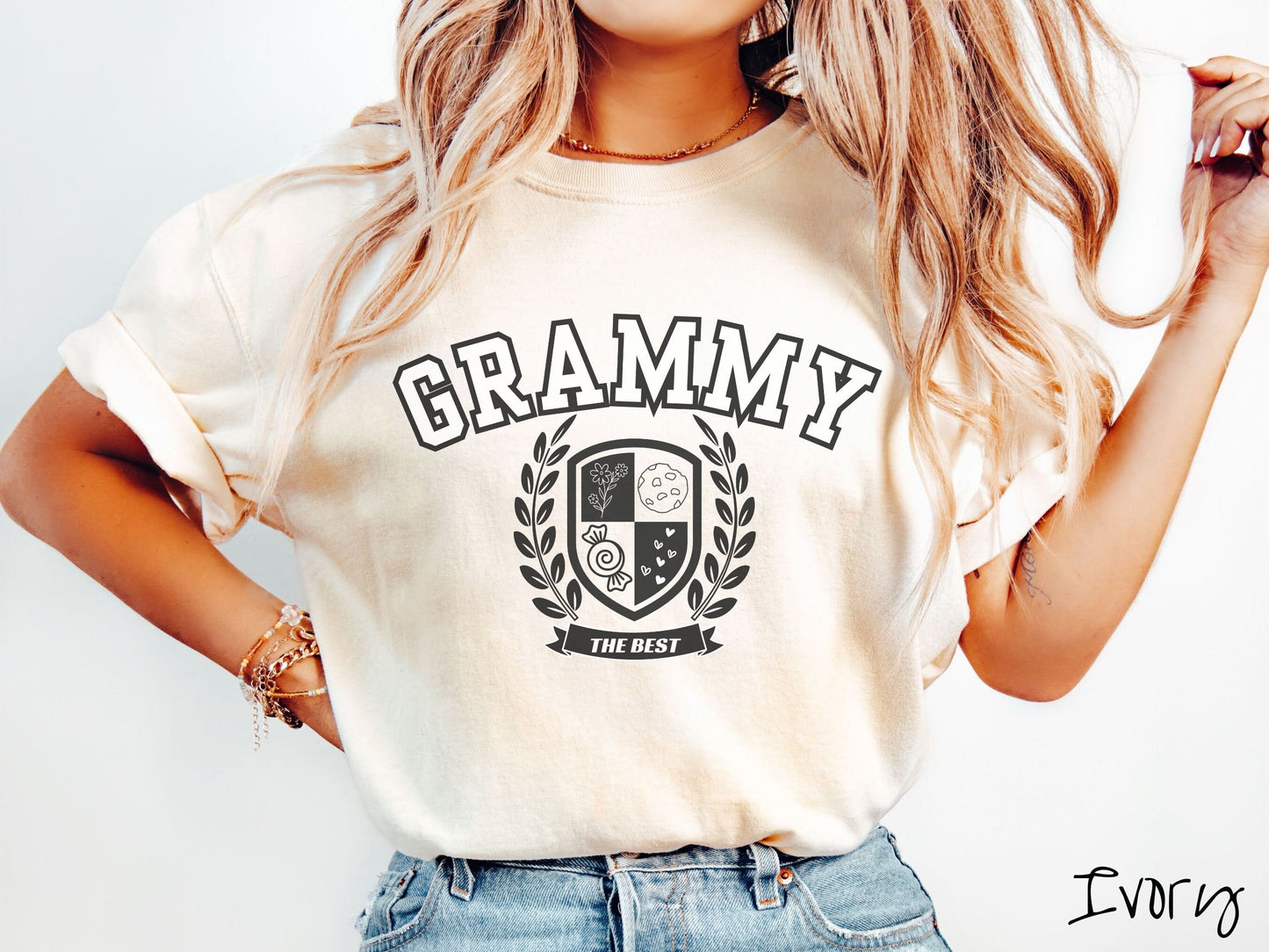 A woman wearing a cute ivory colored shirt with text saying Grammy across the front with a varsity logo underneath with the words The Best centered underneath the logo.