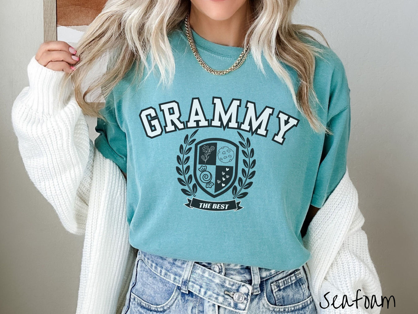 A woman wearing a cute seafoam colored shirt with text saying Grammy across the front with a varsity logo underneath with the words The Best centered underneath the logo.