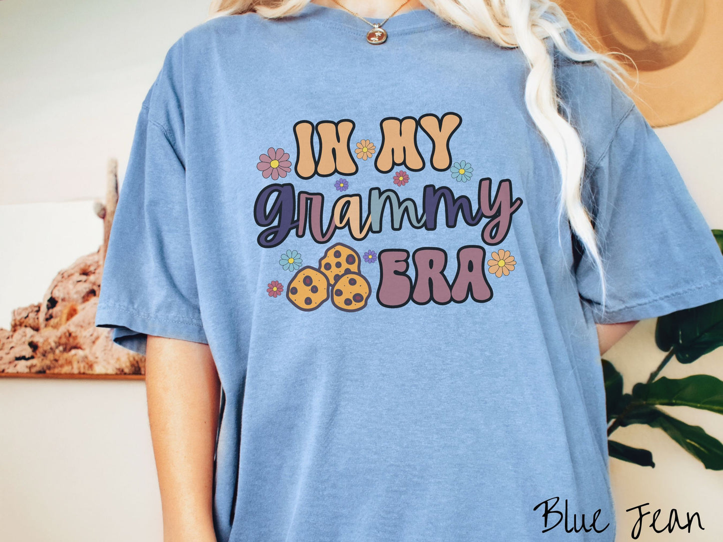 A woman wearing a cute light blue shirt with the text saying In My Grammy era with flowers and chocolate chip cookies mixed within the text.