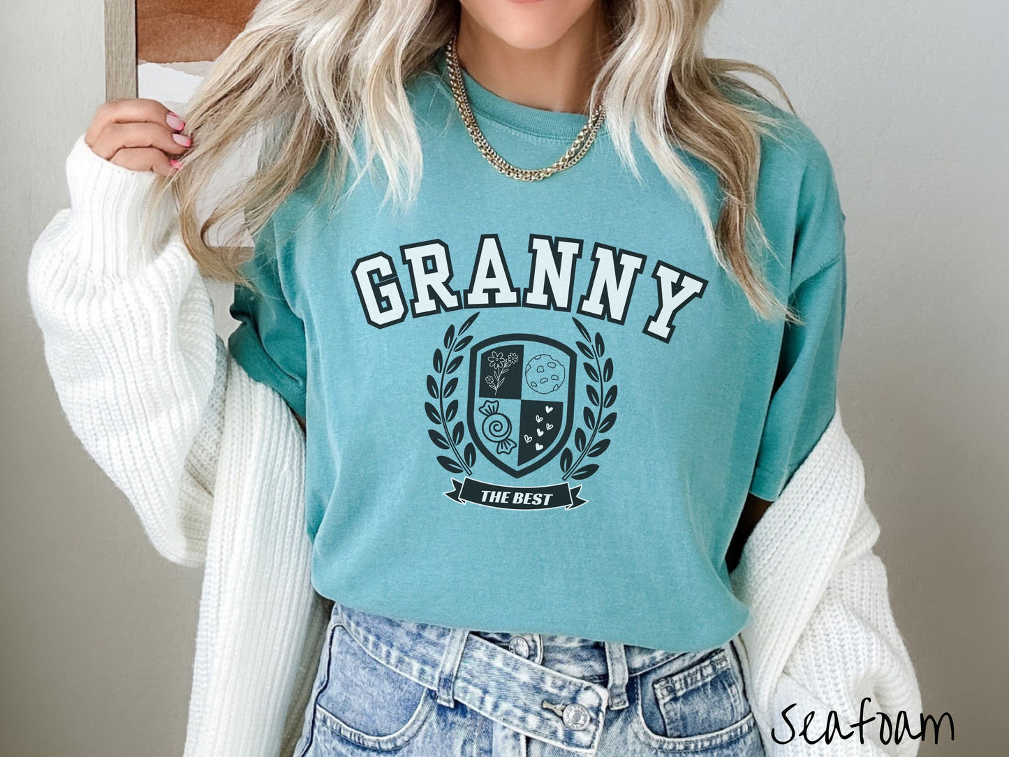 A woman wearing a cute seafoam colored shirt with text saying Granny across the front with a varsity logo underneath with the words The Best centered underneath the logo.