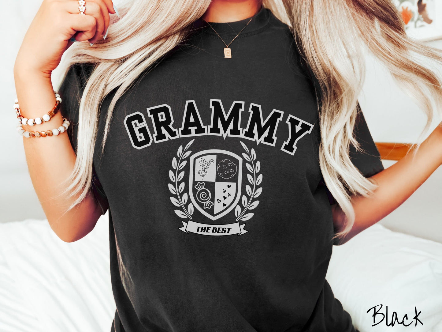 A woman wearing a cute black colored shirt with text saying Grammy across the front with a varsity logo underneath with the words The Best centered underneath the logo.
