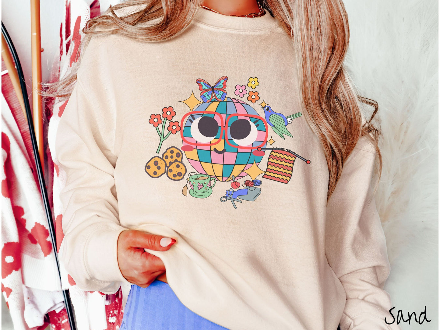 A woman wearing a cute sand colored sweatshirt with a femsale face wearing glasses and smiling