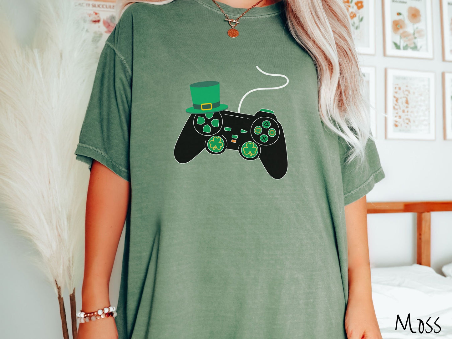 A woman wearing a vintage, moss colored shirt with a black video game controller with green buttons and joysticks, the analog control sticks are in the shape of green leaf clovers, and there is a green top hat hanging off the top left trigger.