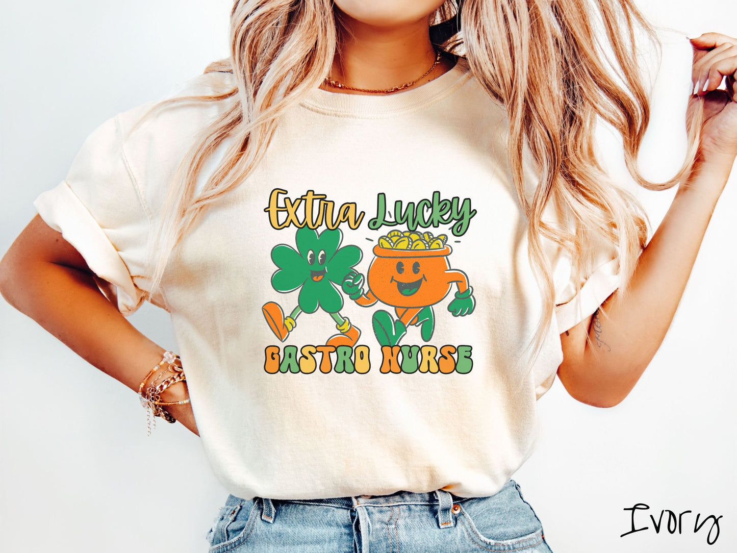 A woman wearing a vintage, ivory colored shirt with the text Extra Lucky Gastro Nurse in yellow, orange, and green font. Between the text are a green clover and orange pot of gold smiling and walking together in step.