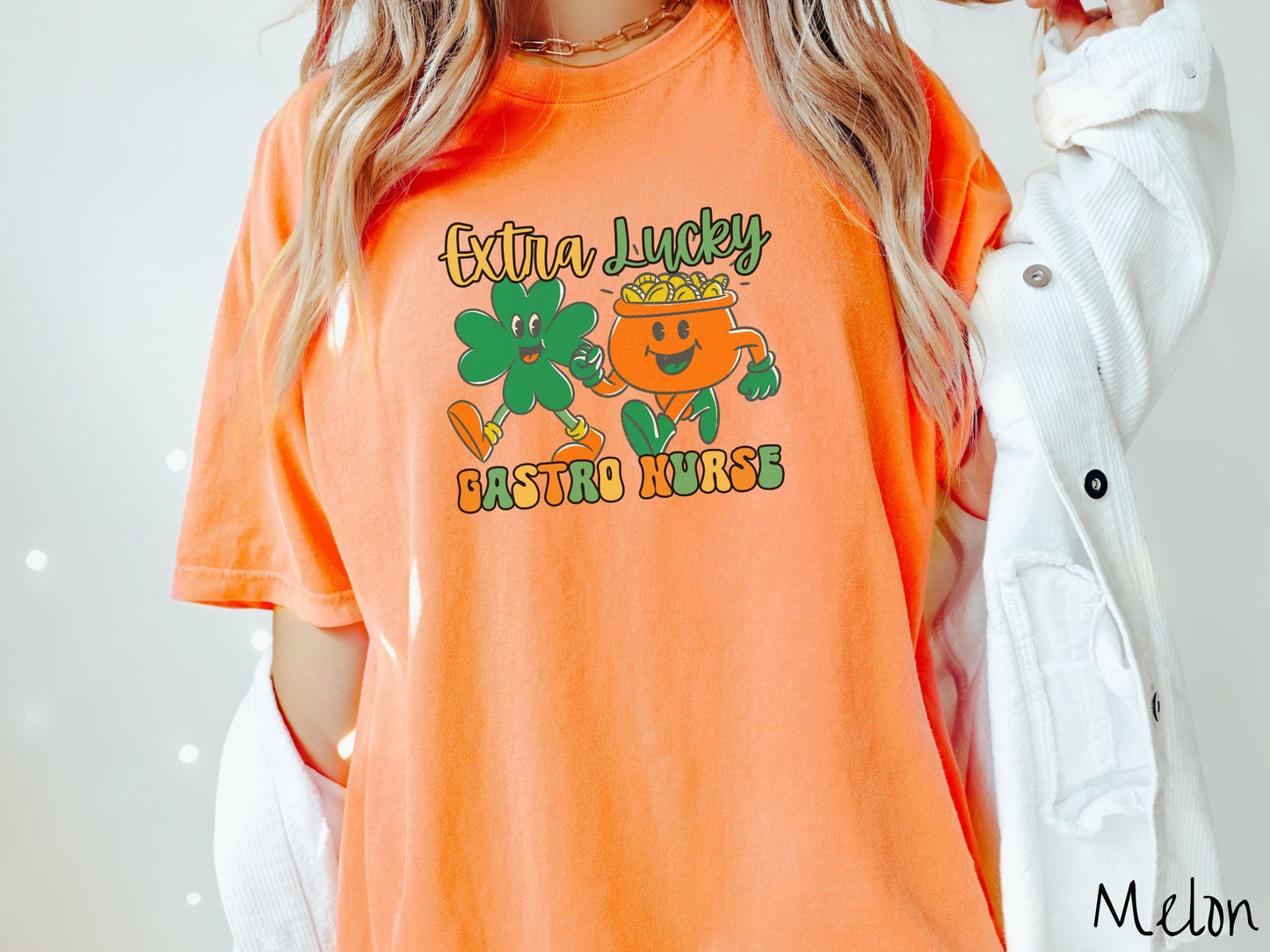 A woman wearing a vintage, melon colored shirt with the text Extra Lucky Gastro Nurse in yellow, orange, and green font. Between the text are a green clover and orange pot of gold smiling and walking together in step.