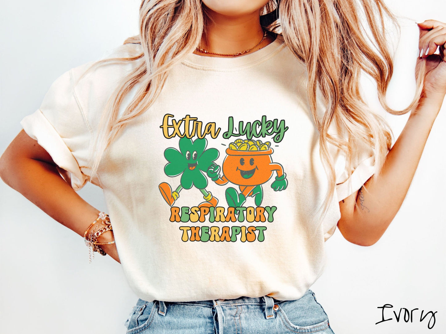 A woman wearing a vintage, ivory colored shirt with the text Extra Lucky Respiratory Therapist in yellow, orange, and green font. Between the text are a green clover and orange pot of gold smiling and walking together in step.