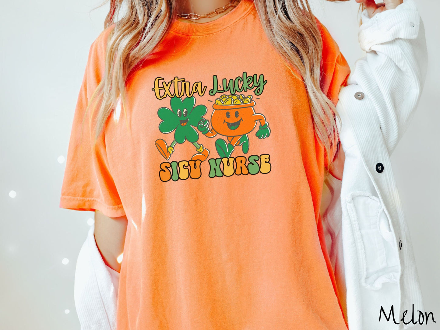 A woman wearing a vintage, melon colored shirt with the text Extra Lucky SICU Nurse in yellow, orange, and green font. Between the text are a green clover and orange pot of gold smiling and walking together in step.