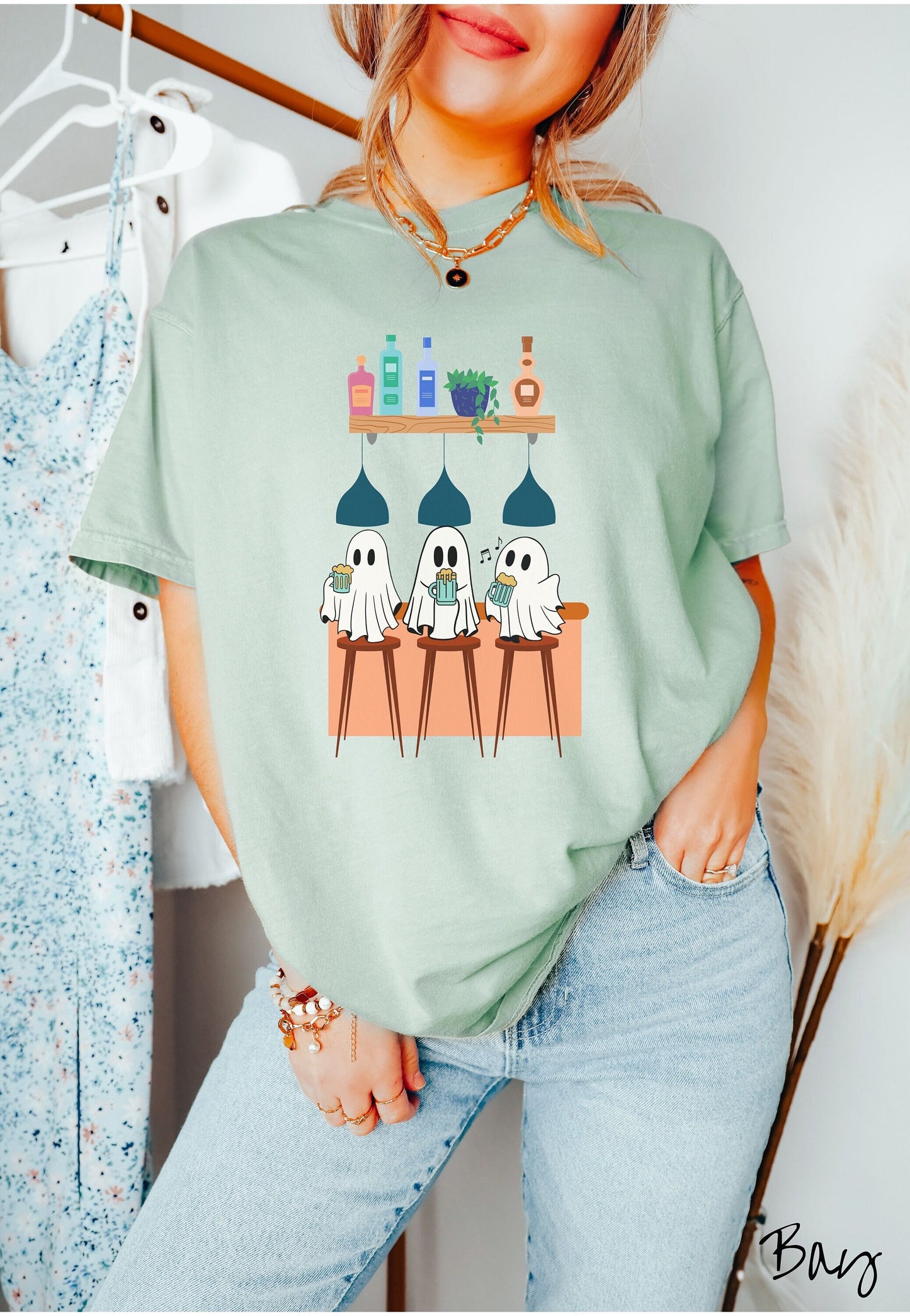A woman wearing a cute bay colored shirt with 3 jovial ghosts with foaming draft beers in hand sitting under lights on bar stools at a trendy bar.