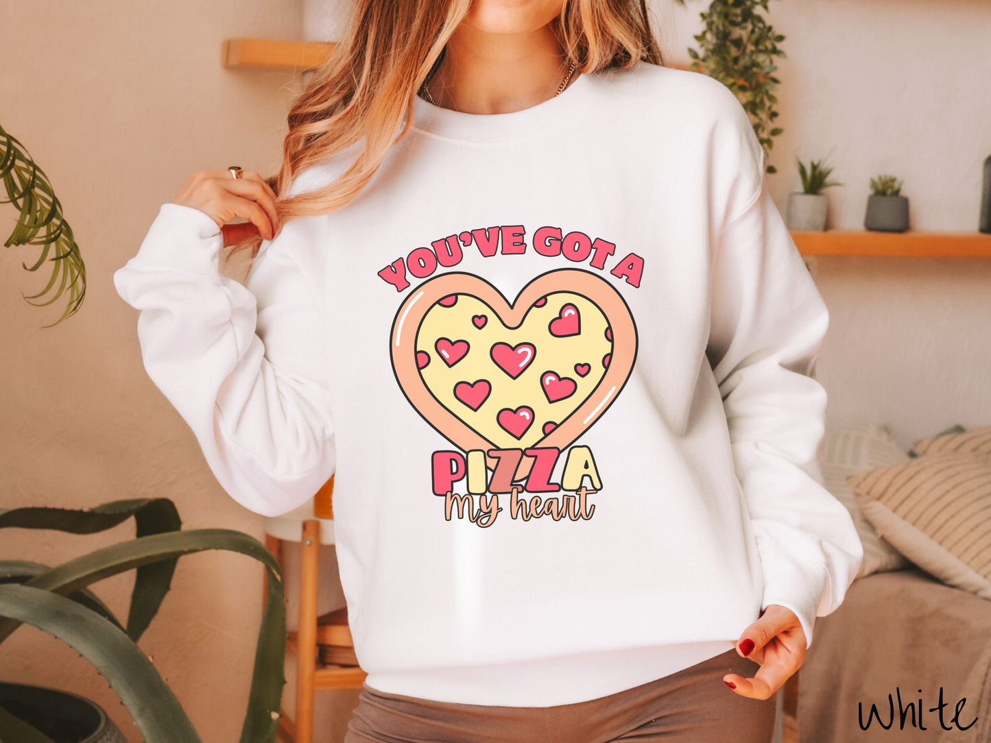 A woman wearing a cute white colored sweatshirt with red text Youve Got a Pizza My Heart around a heart-shaped pizza with heart-shaped red pepperonis.