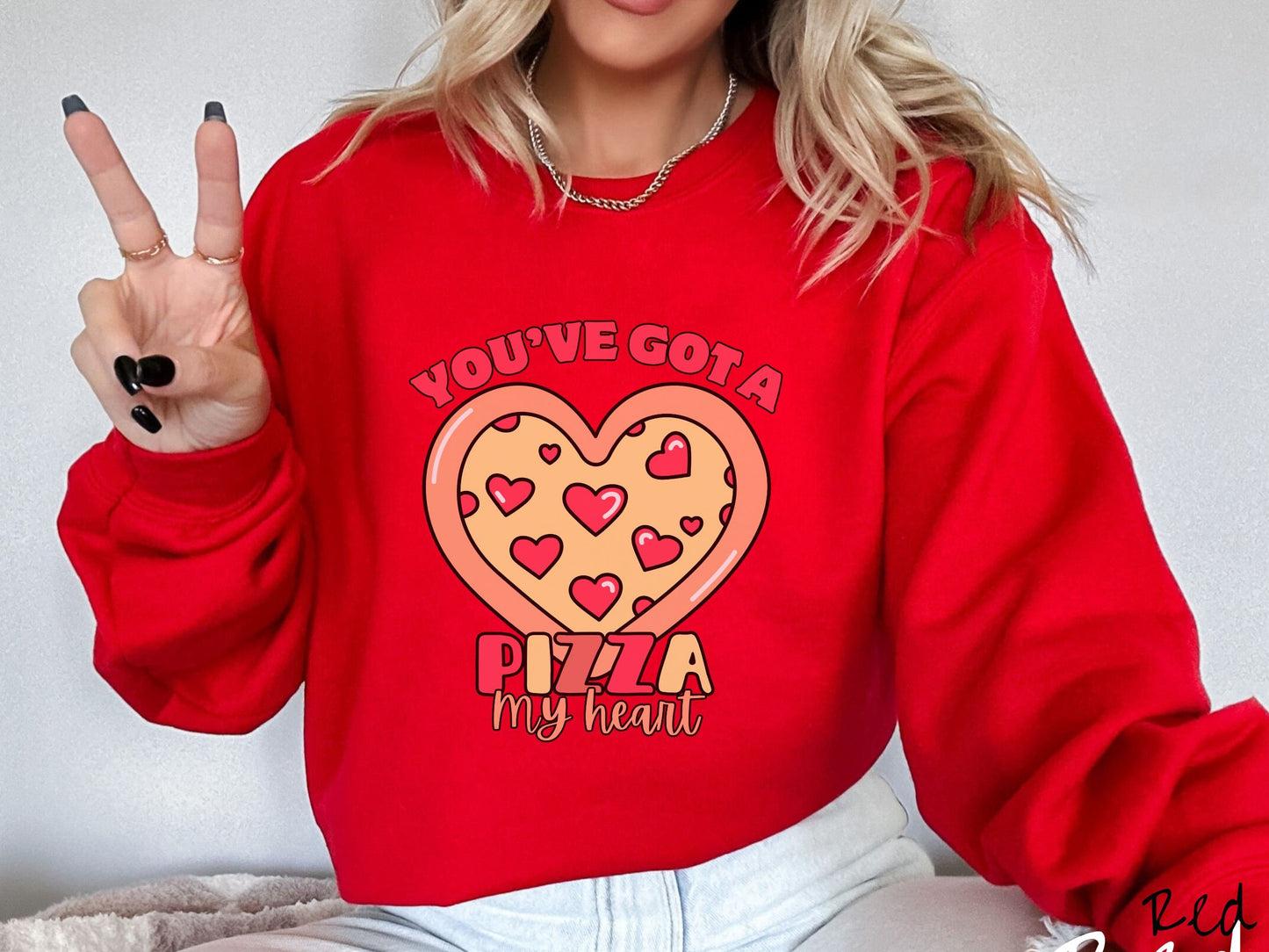 A woman wearing a cute red colored sweatshirt with red text Youve Got a Pizza My Heart around a heart-shaped pizza with heart-shaped red pepperonis.