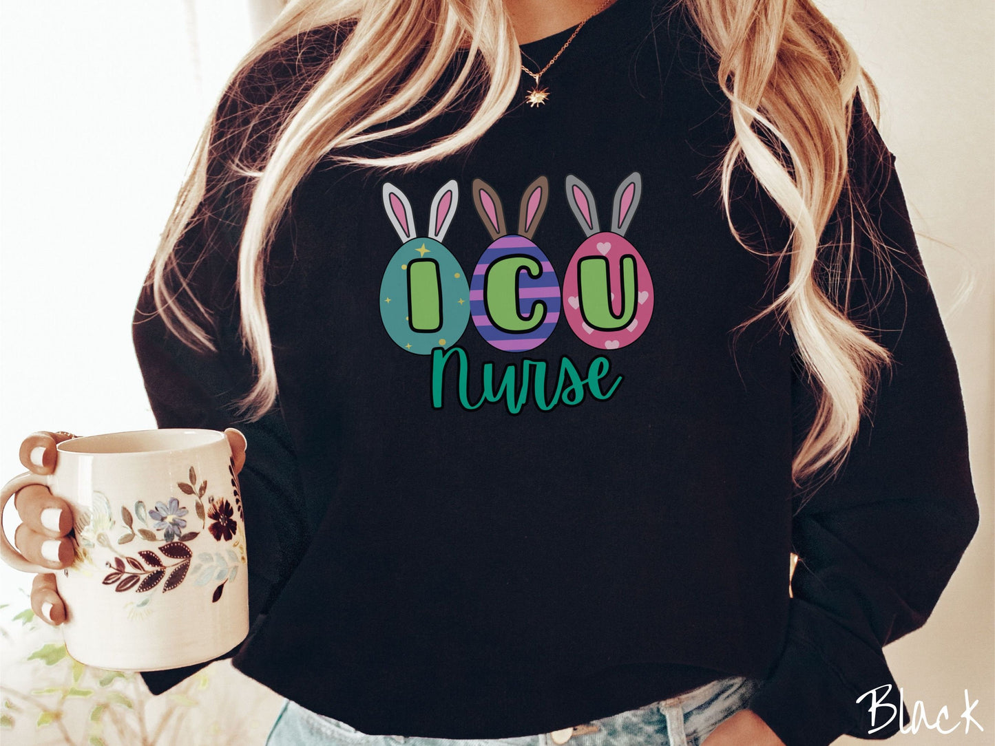 A woman wearing a cute, vintage black colored sweatshirt with three colorful easter eggs next to each other with the letters I, C, and U inside. Each egg has a pair of bunny rabbit ears, one is white, the middle brown, and the left gray.