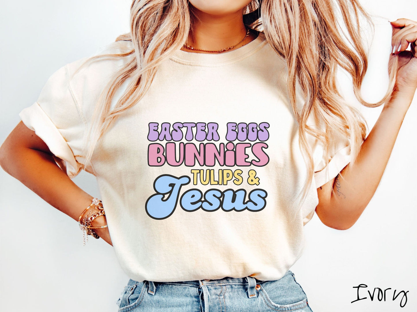 A woman wearing a cute, vintage ivory colored shirt with text Easter Eggs, Bunnies, Tulips, & Jesus in purple, pink, yellow, and blue font.