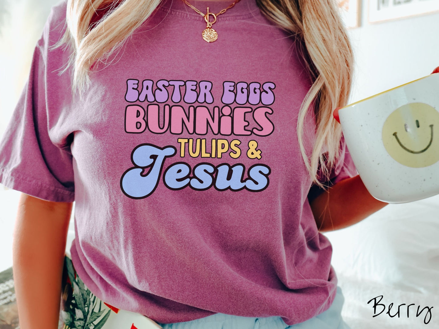 A woman wearing a cute, vintage berry colored shirt with text Easter Eggs, Bunnies, Tulips, & Jesus in purple, pink, yellow, and blue font.