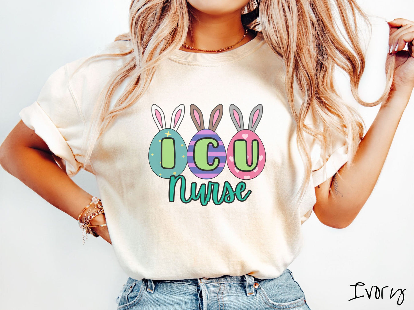 A woman wearing a cute, vintage ivory colored shirt with three colorful easter eggs next to each other with the letters I, C, and U inside. Each egg has a pair of bunny rabbit ears, one is white, the middle brown, and the left gray.