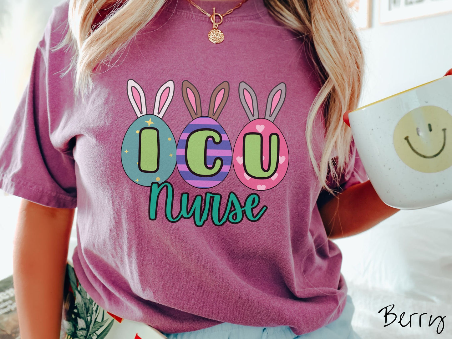 A woman wearing a cute, vintage berry colored shirt with three colorful easter eggs next to each other with the letters I, C, and U inside. Each egg has a pair of bunny rabbit ears, one is white, the middle brown, and the left gray.