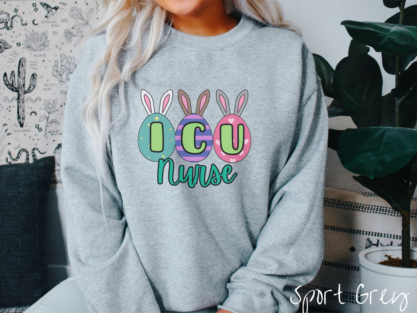 A woman wearing a cute, vintage sport grey colored sweatshirt with three colorful easter eggs next to each other with the letters I, C, and U inside. Each egg has a pair of bunny rabbit ears, one is white, the middle brown, and the left gray.