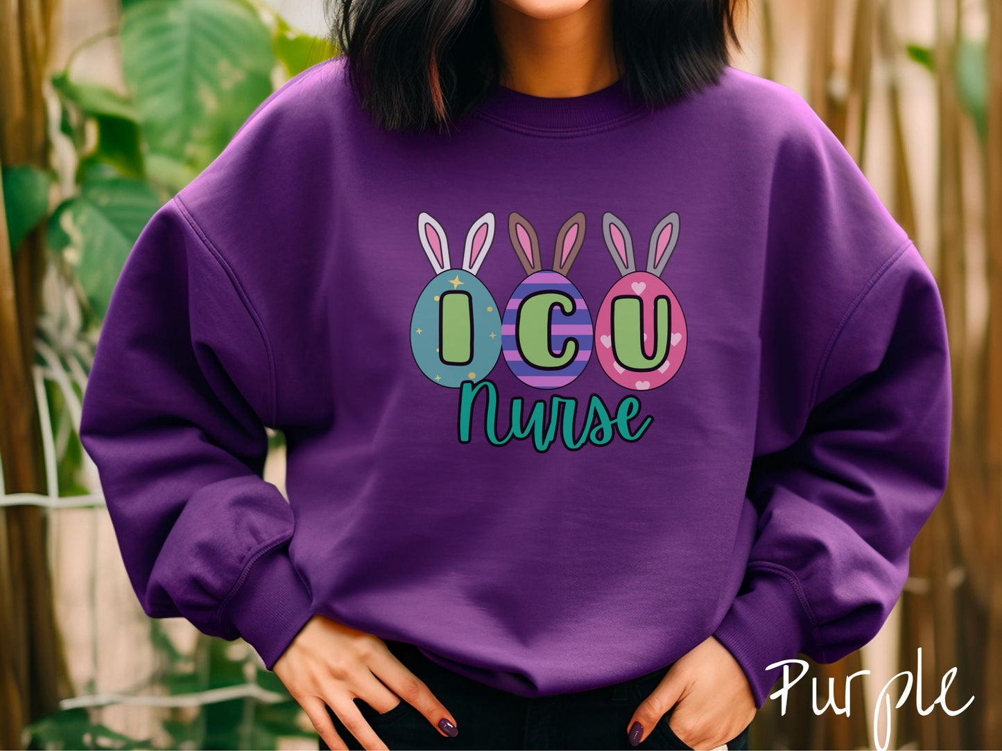 A woman wearing a cute, vintage purple colored sweatshirt with three colorful easter eggs next to each other with the letters I, C, and U inside. Each egg has a pair of bunny rabbit ears, one is white, the middle brown, and the left gray.