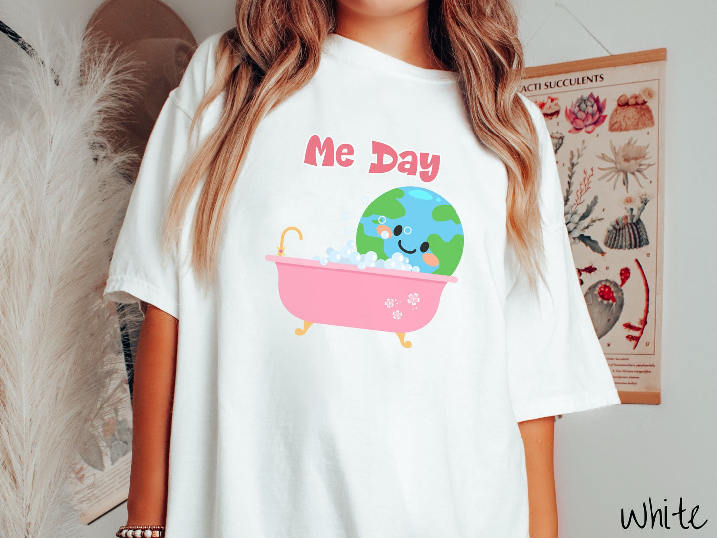 A woman wearing a cute, vintage white colored Comfort Colors shirt with the text Me Day in red font across the top. Below that is the Earth with a smiling face sitting in a pink bathtub enjoying a bubble bath.