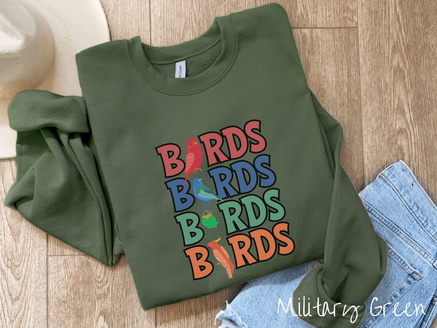 A cute, vintage military green colored comfy sweatshirt with the word BIRDS listed four times vertically in red, blue, green, and orange uppercase font. The Is in BIRDS are different kinds of colorful birds.
