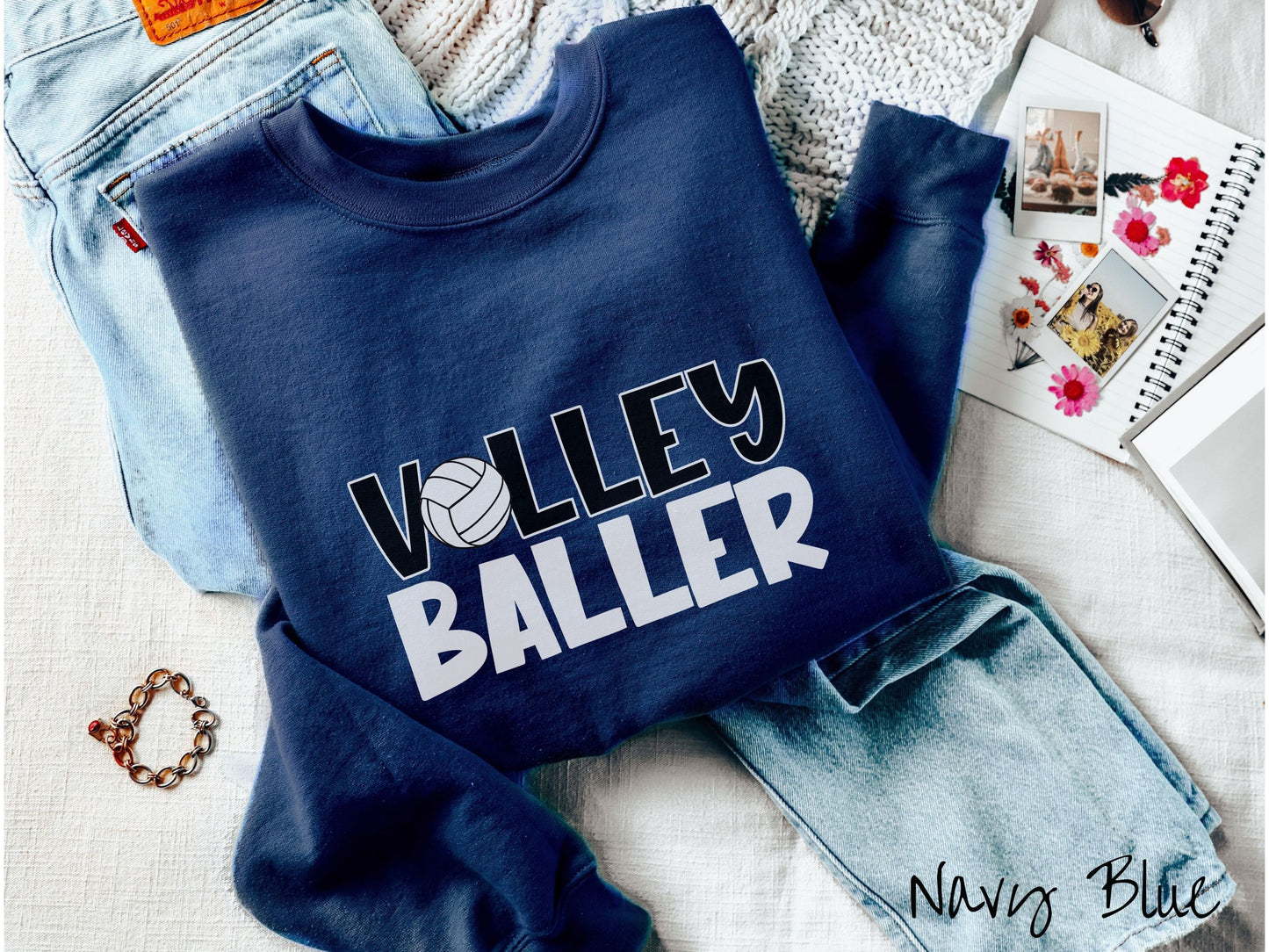 A cute, vintage navy blue colored sweatshirt with the word Volley across the front in black, uppercase font. The O in Volley is a white volleyball. Below that is the word Baller in white, uppercase font.