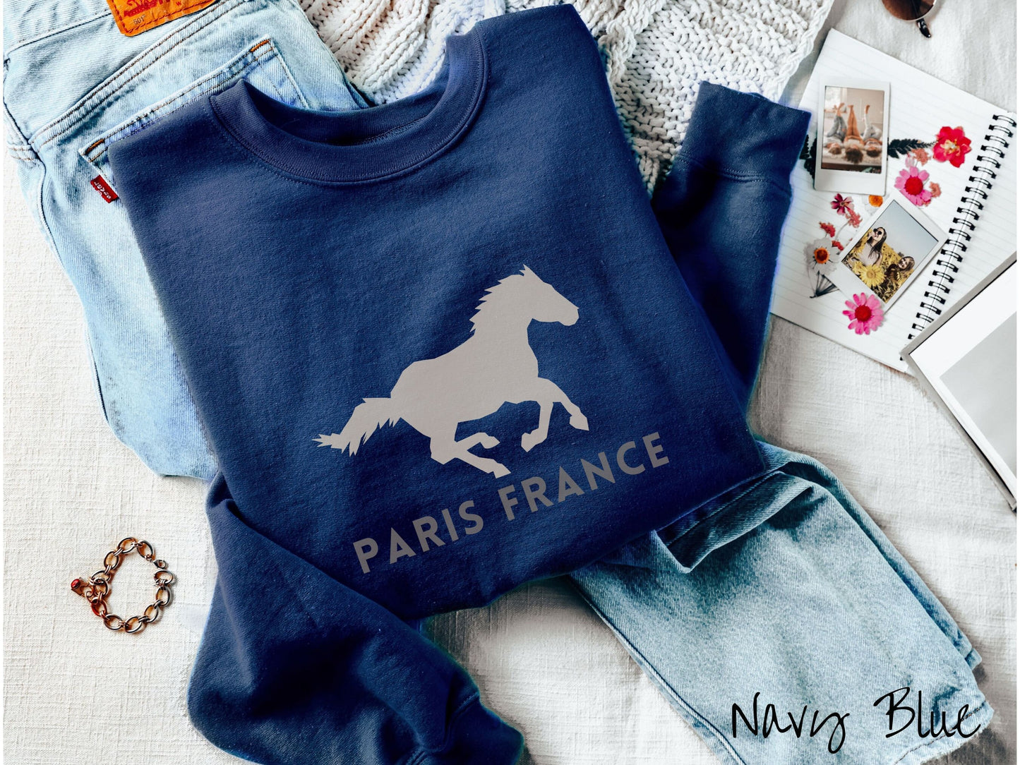 A cute, vintage navy blue colored comfy sweatshirt with a gray silhouette of a running horse across the font. Below it are the words Paris France in gray, uppercase font.