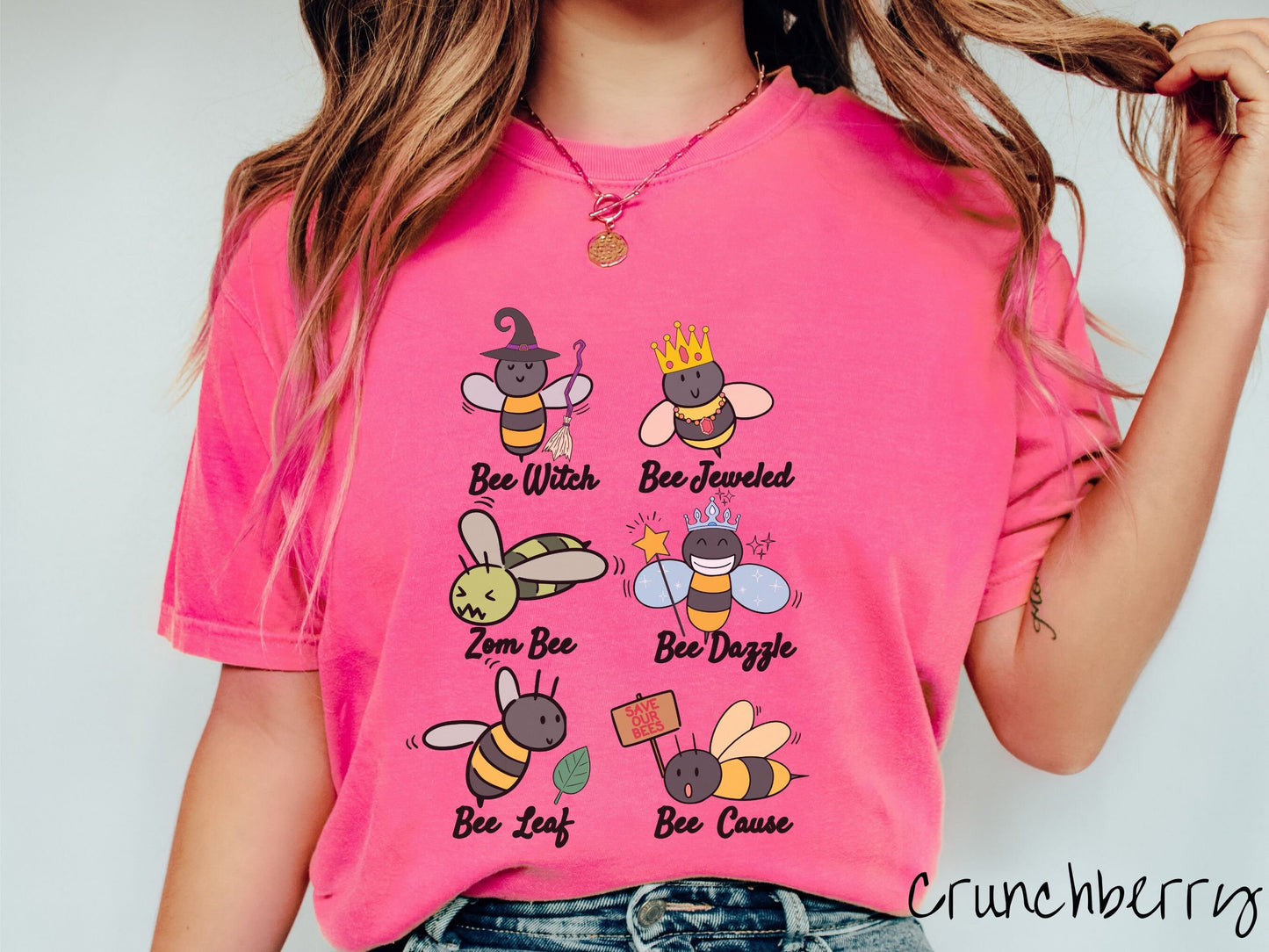 A woman wearing a cute, vintage crunchberry colored comfy sweatshirt that has six puns that play on honey bees accompanied with bee drawings. The puns are Bee Witch, Bee Jeweled, Zom Bee, Bee Dazzle, Bee Leaf, and Bee Cause.