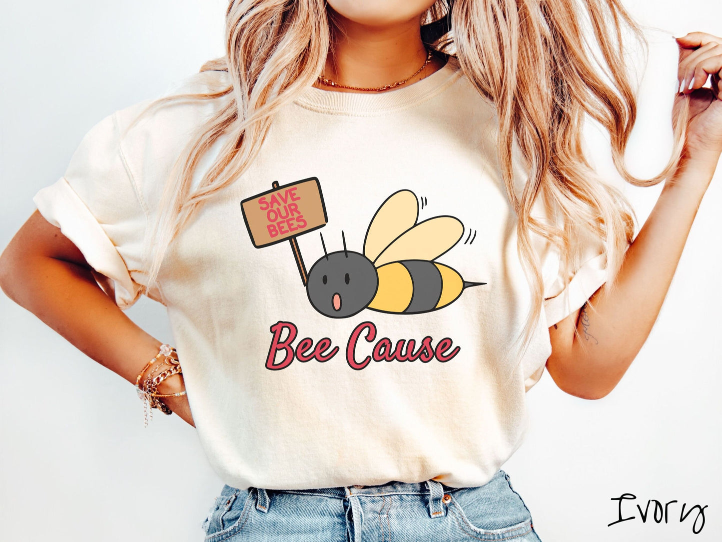 A woman wearing a cute, vintage ivory colored comfy sweatshirt with the text Bee Cause in red, cursive font. Above that is a black and yellow honey bee speaking with its mouth open and holding a sign that reads Save Our Bees in red font.