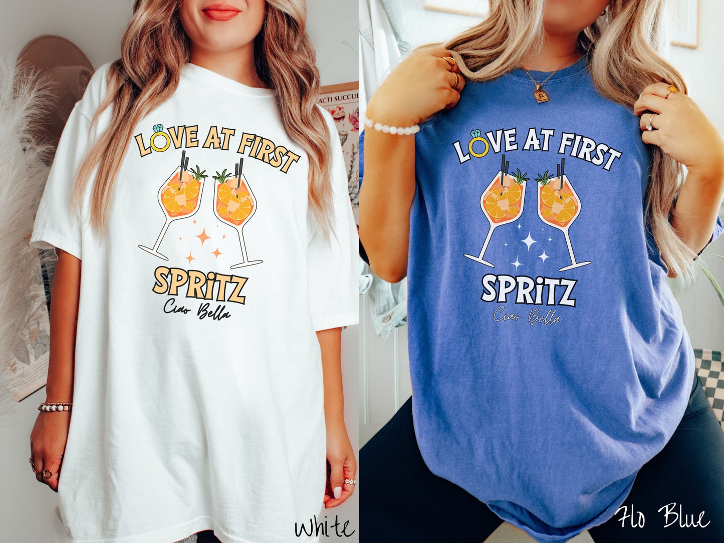 Two women wearing cute, vintage white and flo blue colored Comfort Colors t-shirts with text Love at First Spritz in yellow font, the O in Love is a diamond wedding ring. Between the text are two cocktail glasses of aperol spritz toasting.