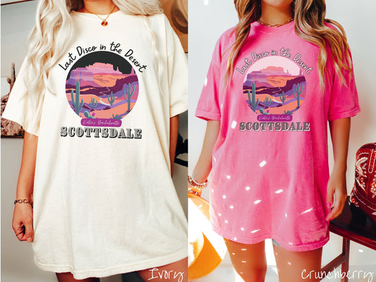 Two women wearing cute, vintage ivory and crunchberry colored Comfort Colors t-shirts with text Last Disco in the Desert and Kate’s Bachelorette Scottsdale, with a picture of the Arizona desert in pink, orange, purple, and green colors.
